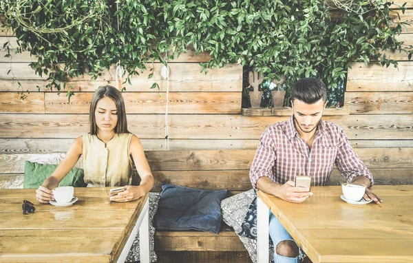 Fashion couple in disinterest moment ignoring each other using mobile cell phone - Concept of apathy sadness addicted to new technologies - Boyfriend and girlfriend break up with smartphones addiction — Stock Photo, Image