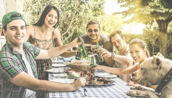 Amigos felices divirtiéndose comiendo y brindando juntos en la barbacoa del jardín del patio trasero - Amistad y concepto familiar con los jóvenes disfrutando de la comida y la cerveza en la fiesta de picnic de la barbacoa de la casa - Filtro retro —  Fotos de Stock