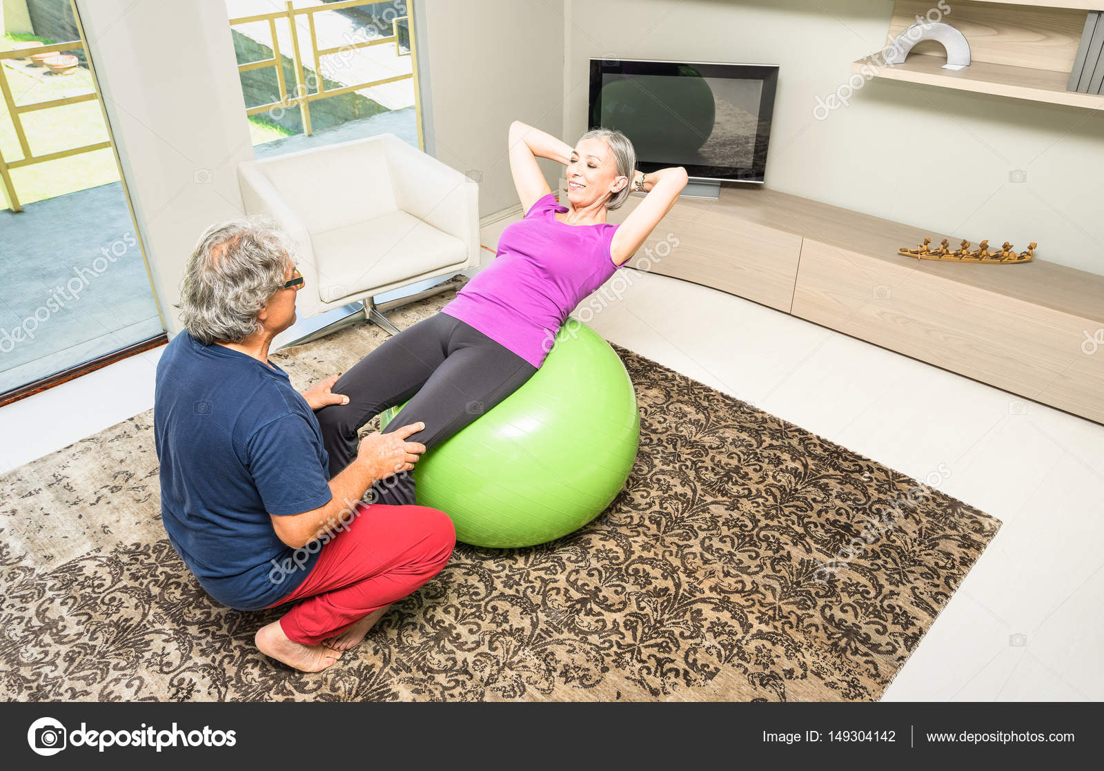 Active elderly couple training with swiss ball at home Retired