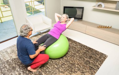 İsviçre topu evde - emekli insanlar jimnastik salonu oturma odasında egzersiz fitness etkinlik, - ile olgun adam hanımefendi kadın crunch sit up karın spor yürütme üzerindeki koçluk eğitimi etkin yaşlı çift