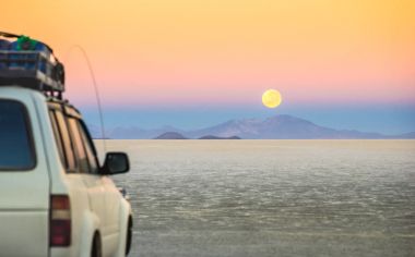 Full moon sunset with off road jeep vehicle on Salar De Uyuni - World famous nature wonder place in Bolivia - Travel and wanderlust concept in South American exclusive landscape - Focus on infinity clipart