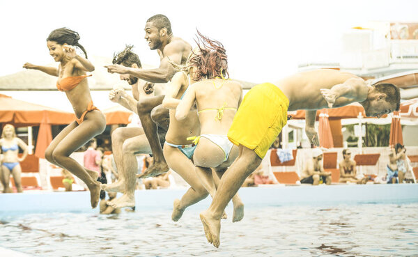 Side view of multiracial friends jumping at swimming pool party - Vacation concept with happy guys and girls having fun in summer day at leisure aquapark - Active young people on retro contrast filter