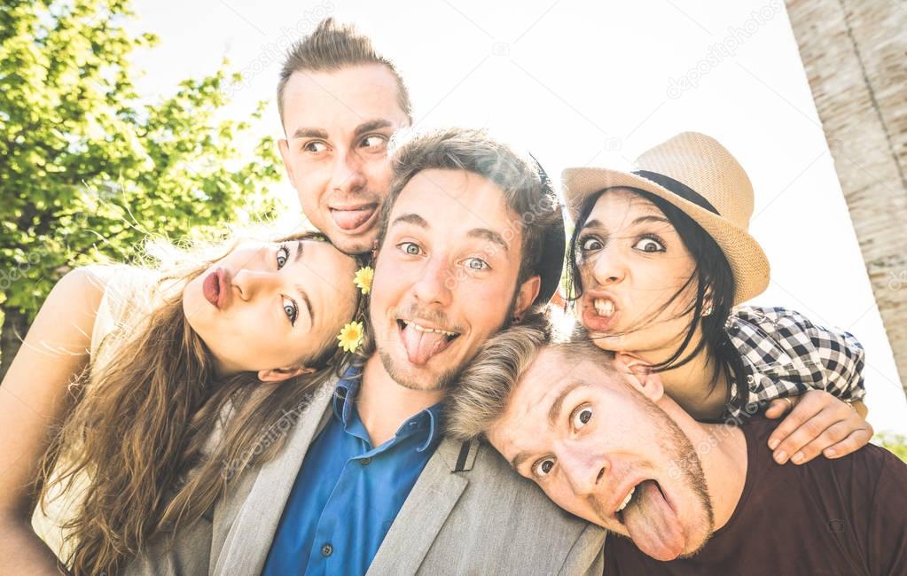 Group of best friends taking selfie outdoor with back lighting - Happy concept with young people having fun together - Cheer and friendship at city tour - Retro vintage filter with focus on middle guy