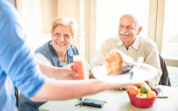 Waiter serving senior couple eating at vegan restaurant - Retired man and woman on active elderly having fun - Happy retirement concept with mature people together - Bright filter with focus on lady — Stock Photo, Image