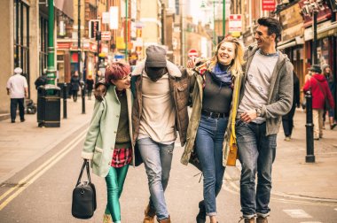 Brick Lane Shoreditch Londra - kış giysileri birlikte eğlenmek çok kültürlü genç kişilerle arkadaşlık kavramı - yumuşak odak sıcak tezat filtre ile yürürken mutlu çok ırklı arkadaşlar