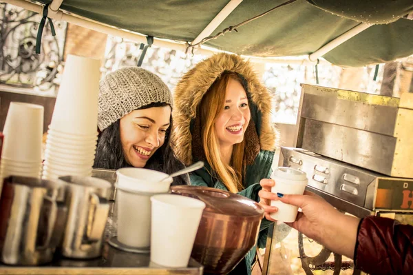 Happy girlfriends best friends sharing time together outdoors at coffee takeaway vendor in winter season - Women friendship concept with joyful girls having fun on deep clothes - Warm vintage filter — Stock Photo, Image