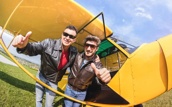 Happy best friends taking selfie at aeroclub with ultra light airplane - Luxury friendship concept about young people with thumbs up having fun together outdoors - Sunny afternoon vivid color tones — Stock Photo, Image