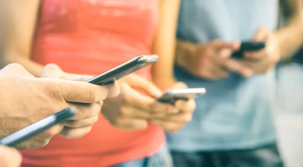 Multiculturele vrienden met behulp van smartphone buitenshuis - mensen handen verslaafd door mobiele smartphone - technologie concept met aangesloten mannen en vrouwen - ondiepe scherptediepte op lichte vintage gefilterde Toon — Stockfoto