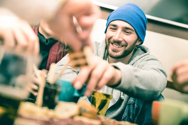 Chico feliz con amigos comiendo comida para los dedos y bebiendo cerveza en el pub - Gente alegre divirtiéndose en la esquina del restaurante del bar cervecero - Concepto de amistad en el filtro desaturado vintage con enfoque en la cara —  Fotos de Stock