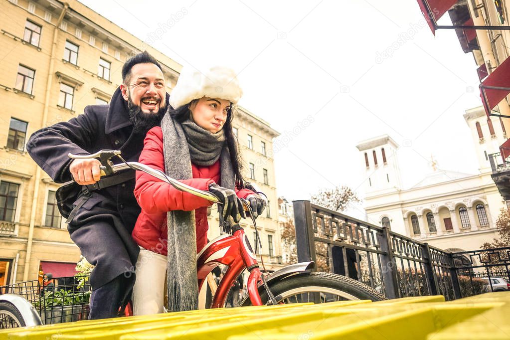 Happy couple in love enjoying winter time outdoor on vintage bicycle - Handsome hipster man with young woman having fun together - Playful relationship concept with travelers boyfriend and girlfriend