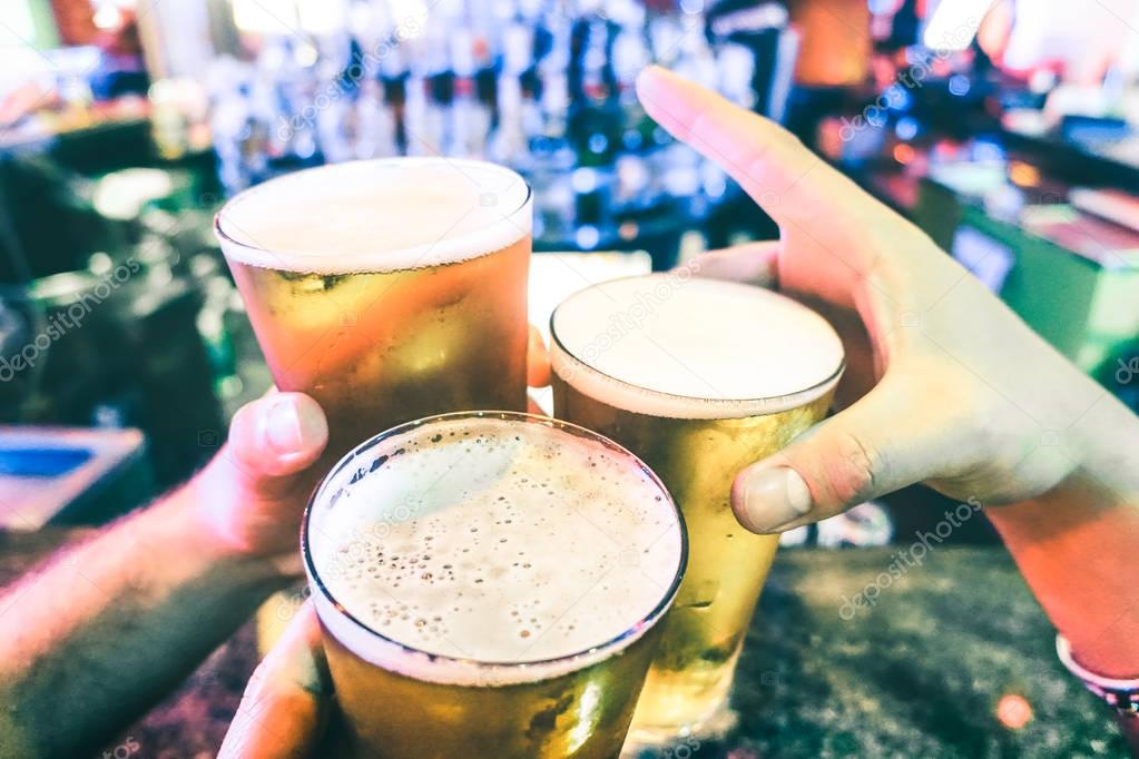 Friend hands toasting beer pints at cocktail bar - Friendship concept with people having fun at brewery party club - Food and drinks fancy evening together - Focus on right glass edge - Vintage filter