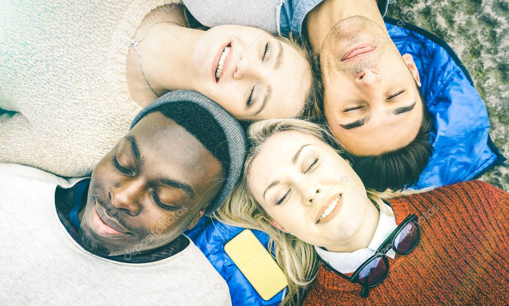 Top view of multiracial best friends having fun resting together outdoors on sunny day - Happy friendship and peace concept with young multicultural people on relax mood - Bright vintage filtered look