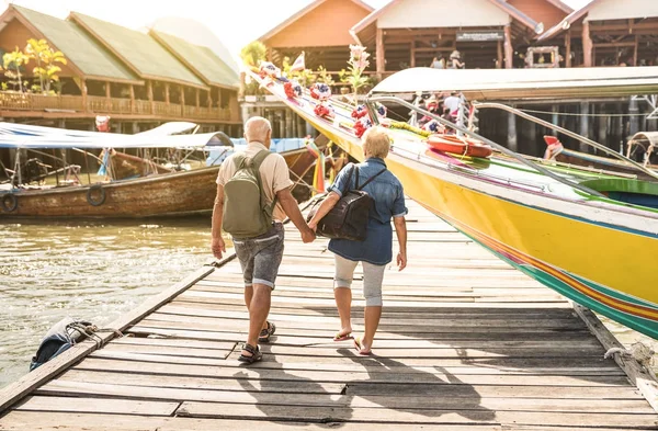 Lyckliga senior paret gå hålla handen på Koh Panyi muslimska flytande byn - aktiva äldre och resor livsstilskoncept med mogna pensionärer på Phang Nga bay Thailand - varm dag filter — Stockfoto