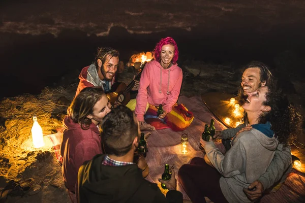 Young hipster friends having fun together at beach camping party by night with campfire light- Friendship travel concept with young people traveler drinking beer at summer surf bonfire -High iso image — Stock Photo, Image