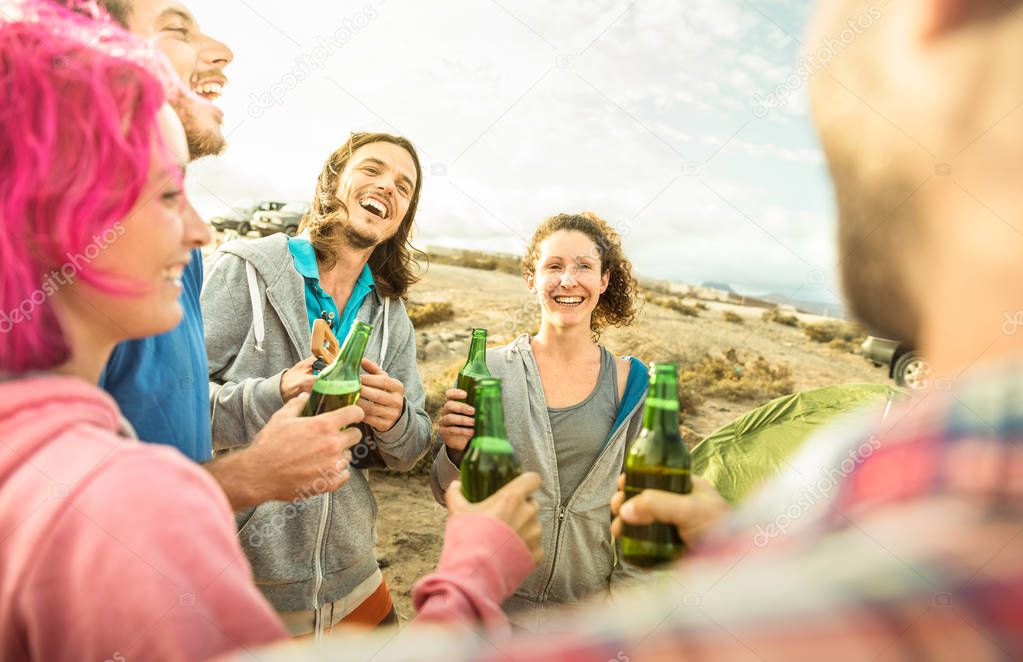 Hipster friends having fun together at beach camping party - Friendship travel concept with young people travelers playing ukulele and drinking bottled beer at summer surf camp - Warm bright filter