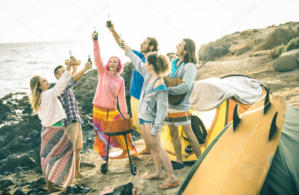 Hipster friends having fun together at beach camping party - Friendship travel concept with young people travelers toasting and drinking bottled beer at summer surf camp - Bright vintage filter