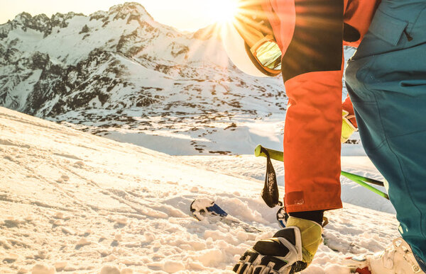Professional skier at sunset touching snow on relax moment in french alps ski resort - Winter sport concept with adventure guy on mountain top ready to ride - Side view point with warm sunshine filter