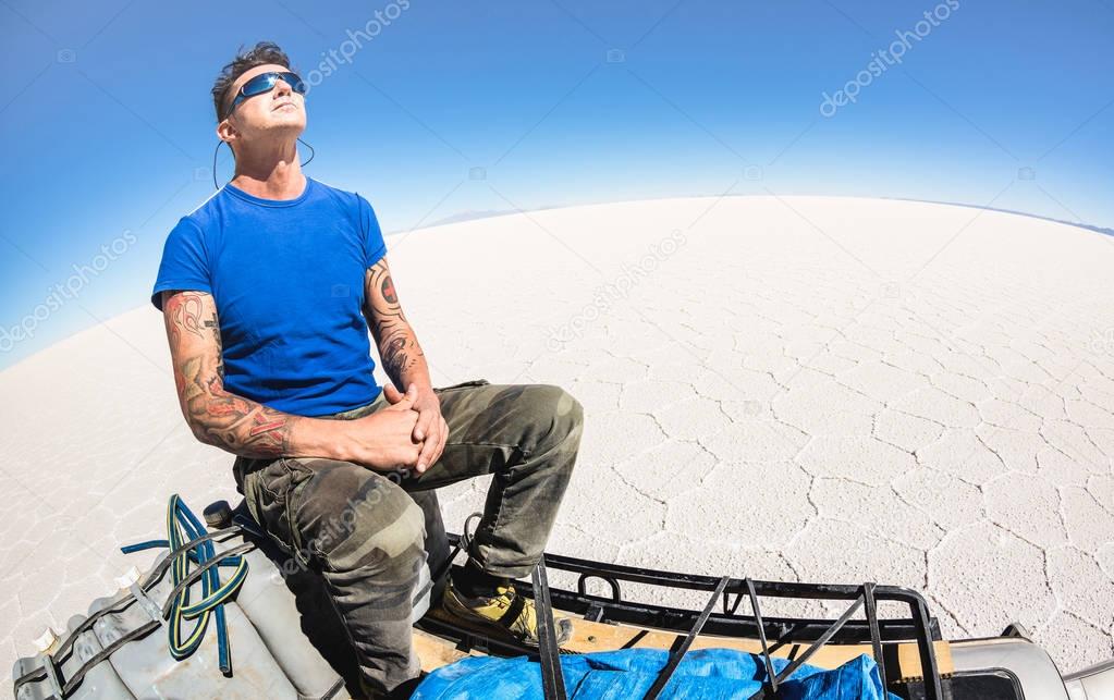 Young man solo traveler taking relax break at Salar de Uyuni saltflats in south american bolivian desert - Adventure wanderlust concept on world famous nature wonder in Bolivia - Bright afternoon tone