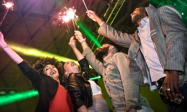 Amigos jóvenes multirraciales bailando en el club nocturno con fuegos artificiales brillantes - Gente feliz divirtiéndose locamente en el club nocturno después de la fiesta - Concepto de vida nocturna borracha con chicos y chicas en el evento del festival de conciertos — Foto de Stock