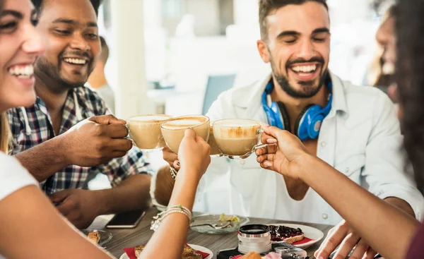 Grupo de amigos bebiendo café con leche en el restaurante cafetería - Personas hablando y divirtiéndose juntos en la cafetería de moda - Concepto de amistad con hombres y mujeres felices en la cafetería - Enfoque en las tazas de capuchino — Foto de Stock