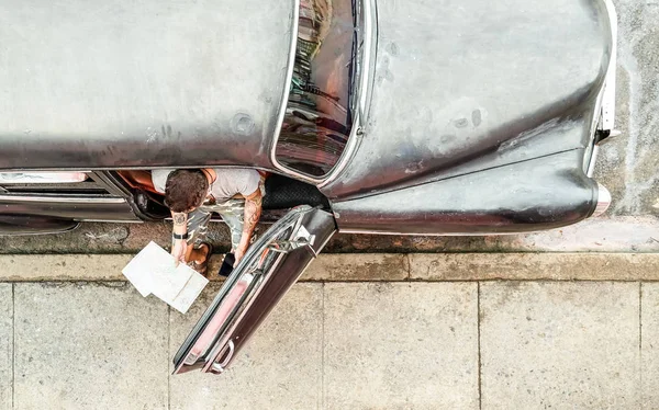 Joven hombre de moda hipster con tatuaje viendo teléfono inteligente móvil en coche vintage durante un viaje por carretera en Cuba - Viajes y tendencias logísticas concepto conectado con el estilo de vida wanderlust - Bright retro filter — Foto de Stock