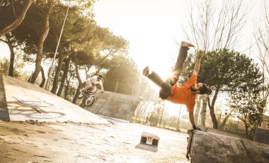 Akrobatik atlama gerçekleştirme kentsel atlet komplike flip skate Park - adam aşırı hareket - Breakdance ve dostluk kavramı - sıcak gün batımı filtre ile dans dostum acrobat arkasında bmx bisiklet sürme