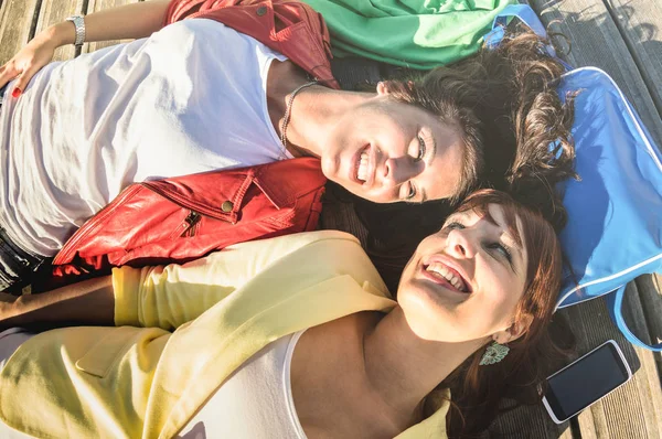 Vista superior de las amigas sonrientes felices tumbadas en el suelo en el momento de relax - Concepto de amistad con las modelos femeninas descansando en la sesión de fotos - Estilo de vida moderno con las mejores amigas mujeres - Filtro cálido brillante —  Fotos de Stock