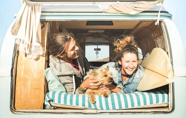 Hipster pareja con lindo perro viajando juntos en la vendimia mini van de transporte - Concepto de inspiración de vida con personas hippies en viaje de aventura en monovolumen en el momento de relax - Brillante cálido filtro retro —  Fotos de Stock