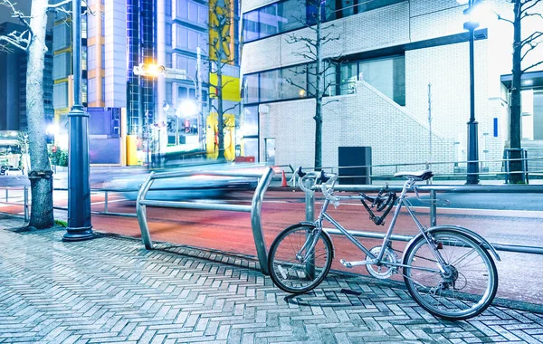 Ночная сцена с припаркованным велосипедом и размытым скоростным автомобилем в центре столицы Японии Токио - концепция городского путешествия с современным велосипедом на ярком лазурном цветном фильтре — стоковое фото