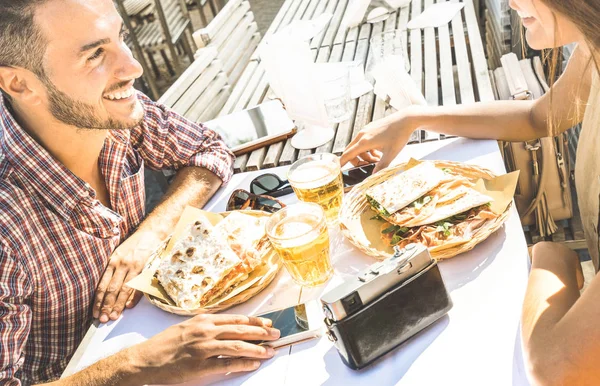 Couple in love having fun at street food restaurant on travel excursion - Young happy tourists enjoying happy moment at beer bar - Relationship concept with focus on guy face and warm bright filter — Stock Photo, Image