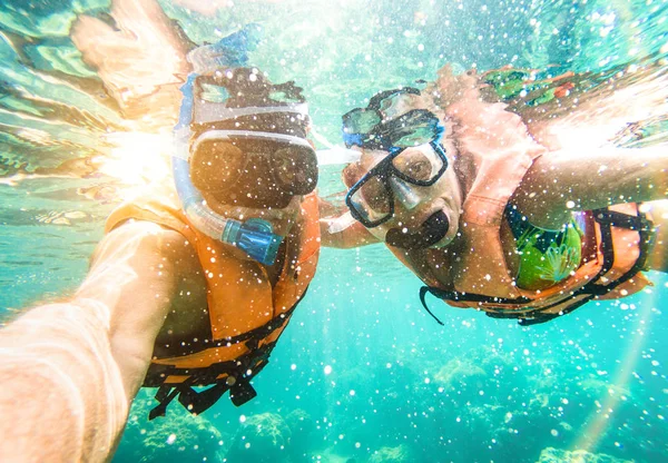 Casal feliz sênior tomando selfie em excursão marítima tropical com câmera de água - Snorkel viagem de barco em cenários exóticos - idoso aposentado ativo e conceito divertido em mergulho - Filtro vívido quente — Fotografia de Stock