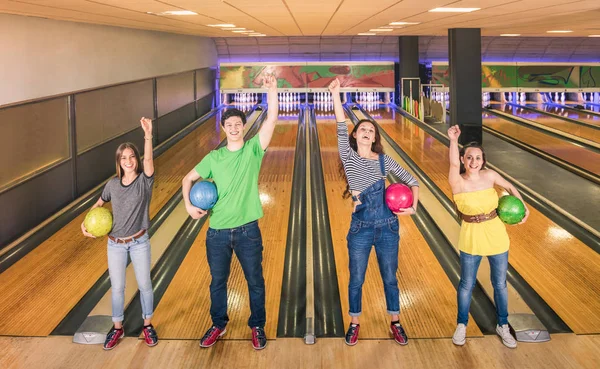 Teman-teman terbaik yang berpose dalam posisi kemenangan di trek bowling melihat ke kamera - persahabatan dan konsep hobi dengan orang-orang muda bermain-main bersenang-senang dan berbagi waktu bersama - Tampilan yang hangat disaring — Stok Foto