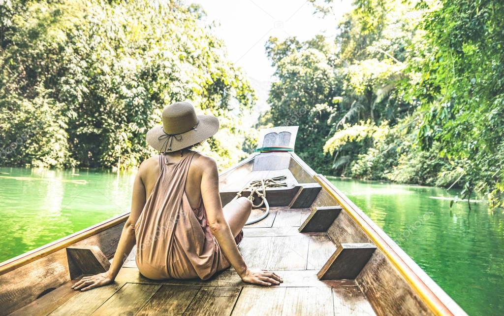 Young woman traveler on longtail boat trip at island hopping in Cheow Lan Lake - Wanderlust and travel concept with adventure girl tourist wanderer on excursion in Thailand - Warm greenish filter