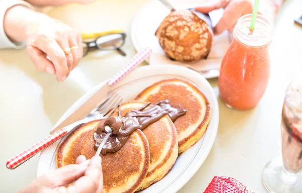 Para starszych naleśniki z czekoladą w coffee bar - dojrzałe osoby ręce na śniadanie z górnego punktu widzenia - koncepcja żywności i napojów z emerytowanych mężczyzn i kobieta - ciepły jasny filtr — Zdjęcie stockowe