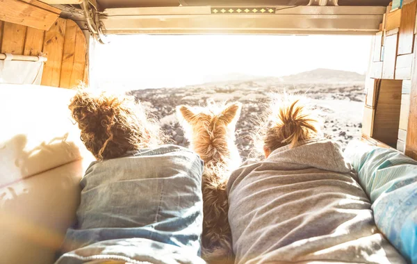Pareja hipster con lindo perro viajando juntos en transporte de furgonetas vintage - Concepto de inspiración de vida con personas hippies en viaje de aventura en minivan viendo la puesta de sol en el momento del amor - Filtro cálido sol —  Fotos de Stock