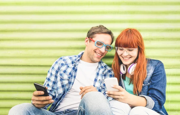 快乐的年轻夫妇玩手机智能手机在老式的垃圾位置-友谊概念与时髦的好友连接新技术-千年一代在线交友 — 图库照片