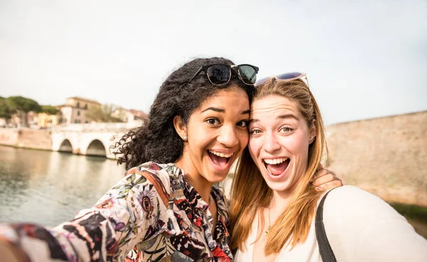 Happy multiracial girlfriends taking selfie and having fun outddors - Friendship concept with girls at spring break travel - Modern lifestyle with female best friends women - Bright day filter tone — Stock Photo, Image