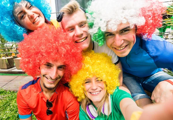 Aficionados aficionados al fútbol amigos tomando selfie después de partido de copa de fútbol colgando alrededor juntos - Grupo de jóvenes con camisetas multicolores y pelucas que se divierten en el campeonato mundial de deporte —  Fotos de Stock