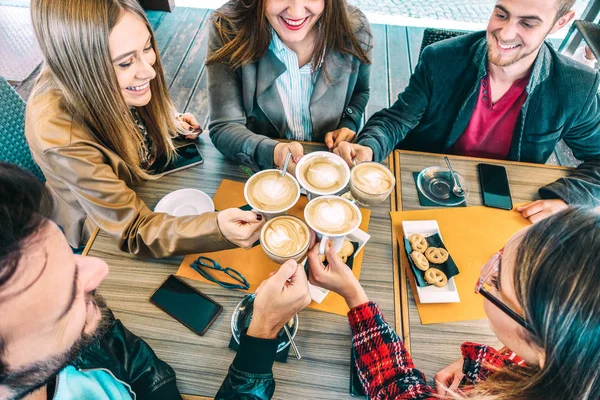 Top view of happy friends toasting cappuccino drink at coffee shop restaurant - Millennial people group having fun on breakfast together at fashion cafe bar - Friendship concept on vivid warm filter — Stock Photo, Image