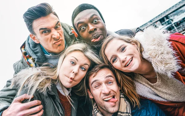 Mejores amigos multirraciales tomando selfie al aire libre en ropa de invierno de otoño - Concepto de juventud feliz con gente milenaria divirtiéndose juntos - Amistad multicultural contra el racismo - Brillante filtro vívido —  Fotos de Stock