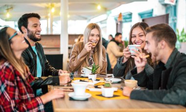 Arkadaş grubu kahve barında cappuccino içiyor - insanlar süslü kafeteryada sohbet ediyor ve eğleniyorlar - Restoran kafeteryasında mutlu erkekler ve kızlarla arkadaşlık konsepti - sıcak ampul ışığı filtresi