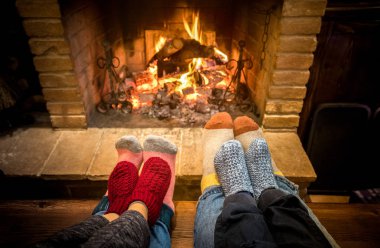 Anne baba ve çocuklar Noel zamanı rahat şöminede oturuyorlar - güzel bir aile evde yünlü çorapların üzerinde dinleniyor - kış tatili ve sıcak ateş filtresi üzerine x mas konsepti