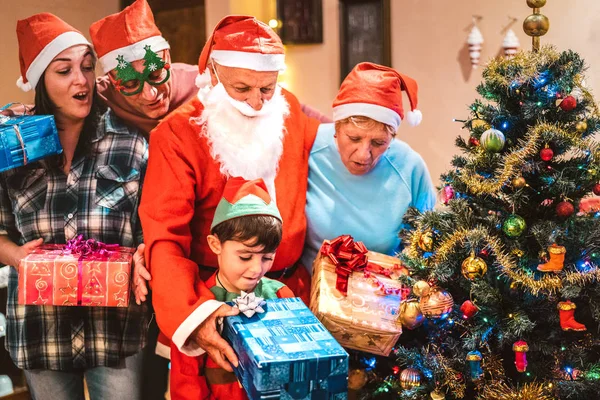 Família de várias gerações se divertindo na noite de Natal dando uns aos outros x mas presentes - Conceito de férias de inverno com pais e filhos abrindo presentes juntos - Foco no rosto do avô e sobrinho — Fotografia de Stock