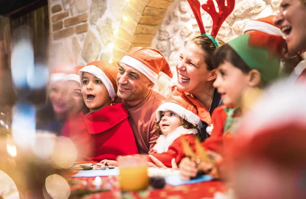 ครอบครัวหลายชั่วอายุคนในชุดหมวกซานต้า มีความสนุกสนานในงานเทศกาลคริสต์มาส บ้านปาร์ตี้ โพสสําหรับภาพถ่ายกลุ่ม แนวคิดวันหยุดฤดูหนาว x mas กับพ่อแม่และเด็ก ๆ กินด้วยกัน ตัวกรองสีแดงอบอุ่น — ภาพถ่ายสต็อก