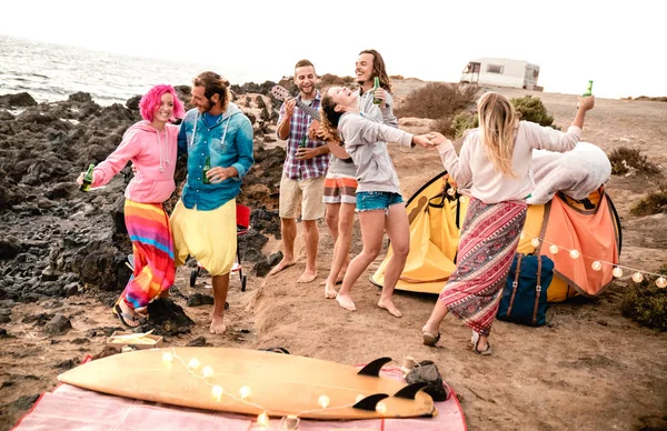 Hipster friends having fun together at beach party on camping time - Wanderlust and alternative travel concept with young people dancing and drinking beer at summer surf camp - Warm vintage filter — Stock Photo, Image
