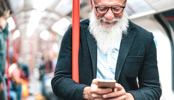 河马大胡子男子在地铁中使用手机.时髦的成年人用智能手机查看时间表.无年龄限制的快乐生活方式和技术概念.室内霓虹灯过滤器 — 图库照片