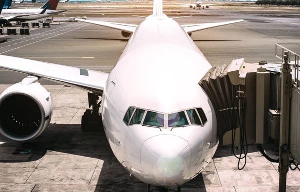 離陸準備ができている空港滑走路近くの飛行機のフロントビュー-国際線ターミナルゲートで飛行機で世界中の放浪者の旅行のコンセプト-サンフレアハローと暖かいコントラストフィルター — ストック写真