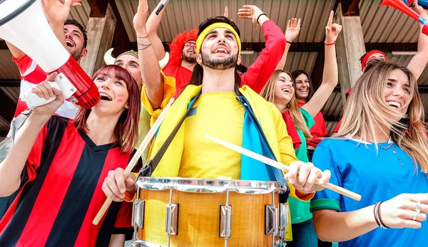 Soccer fan supporters cheering and watching football cup match at intenational stadium bleachers - Sport concept with young people group with multicolor t-shirts having excited fun world championship — Stock Photo, Image