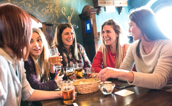 Happy women drinking beer at brewery restaurant - Female friendship concept with young girlfriends enjoying time together and having genuine fun at cool vintage pub - High iso image with soft focus — 스톡 사진