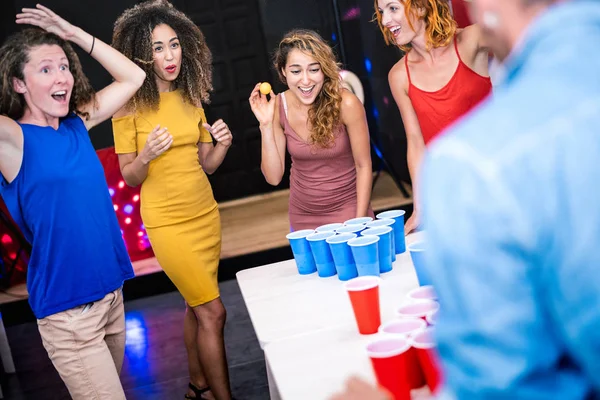 Happy friends group playing beer pong in youth hostel - Travel and fun concept with backpackers having genuine fun together at guesthouse gameroom - Vivid color filter with focus girl throwing ball — 스톡 사진